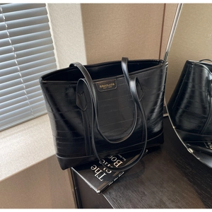 Close-up of black leather tote bag with Meiduola logo and textured glossy finish