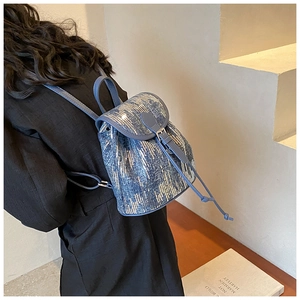 Détail du sac à dos en denim bleu avec paillettes argentées et bretelles réglables
