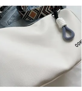 Close-up of white canvas bag's soft twill fabric and geometric woven shoulder strap
