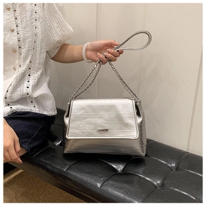 Detail showing the silver textured leather texture and metal chain strap on the tote bag