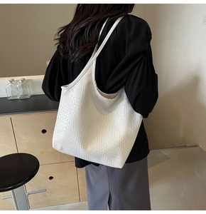 Detailed view of white woven texture on a large capacity tote bag worn by a model
