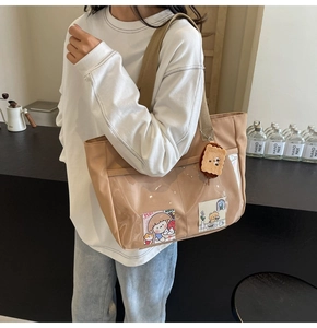 Detail of light brown nylon tote bag with transparent PVC pocket and plush keychain