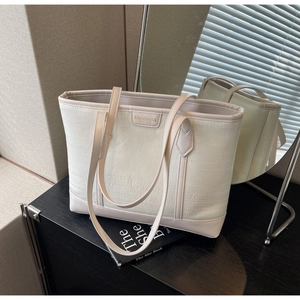 Close-up of cream tote bag with textured fabric surface and Meiduola logo plate
