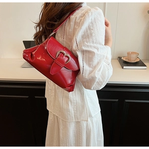 Detail of red leather shoulder bag with silver heart buckle styled on an arm