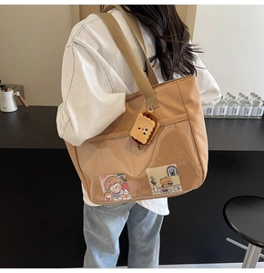 Khaki nylon ita bag with large clear PVC window and plush biscuit charm shown on shoulder