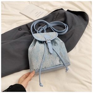 Détail d'un sac à dos en jean bleu clair avec paillettes argentées et cordon de serrage