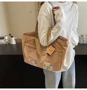 Detail view of khaki nylon tote bag with PVC window and cute biscuit plush charm