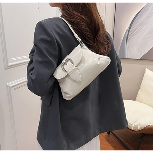 Detail of creamy white underarm bag featuring a metallic heart clasp on smooth faux leather