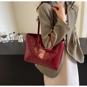 Detail view of large red tote bag with crocodile pattern and dual handle design