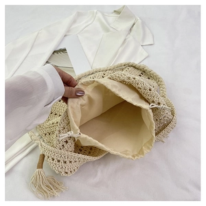 Gros plan détaillé d'un sac cabas tissé crème avec texture crochetée et pompon décoratif