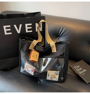 Detail of black nylon tote bag with transparent PVC front pocket and cute charms