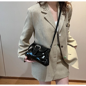Detail of black glossy shoulder bag with a large silver heart buckle on a model