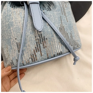 Détail d'un mini sac à dos en jean avec paillettes argentées et cordon de serrage