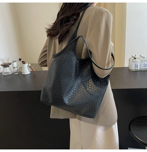 Detailed view of black woven texture tote bag featuring Intrecciato leather craftsmanship