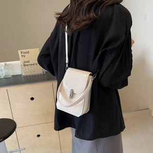 Mini sac bandoulière chic en cuir beige avec fermoir argenté porté par un mannequin
