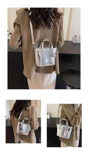 Detail view of silver crossbody bucket bag with metallic ball charm and shiny finish