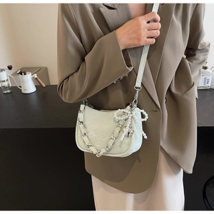Detail of mint green leather shoulder bag with silver chain and pearl bow charm