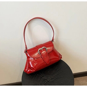 Détail du sac selle en cuir verni rouge brillant avec boucle cœur argentée et plis chic