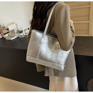 Detail of silver textured leather tote bag featuring sleek metallic brand logo and long strap