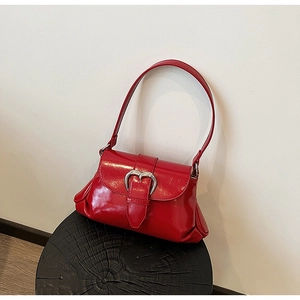 Detail of red patent leather shoulder bag with a silver heart-shaped metal buckle