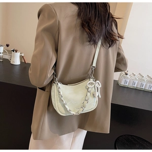 Detail of mint green half-moon bag featuring silver chain and pearl bow charm