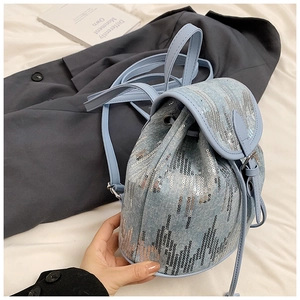 Détail d'un mini sac à dos en denim avec paillettes argentées et fermeture à cordon