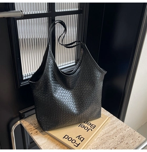 Detail of black woven tote bag showing the intricate faux leather criss-cross texture