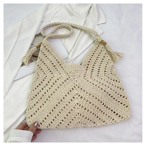 Gros plan du sac fourre-tout beige ajouré avec pompon bohème et bandoulière tressée