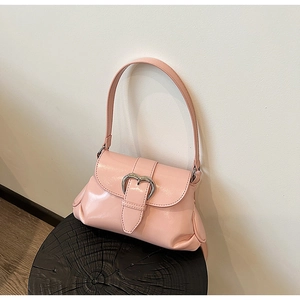 Detail of light pink patent leather shoulder bag with a silver heart-shaped metal buckle