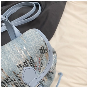Détail du mini sac à dos en jean bleu clair avec rayures verticales à paillettes argentées