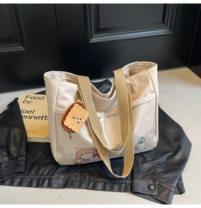 Detail of beige nylon tote bag with transparent PVC pocket and cute biscuit charm