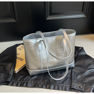 Detail of silver metallic tote bag with pleated texture and sleek brand logo tag