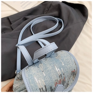 Gros plan d'un mini sac à dos en jean bleu clair avec paillettes argentées et cuir