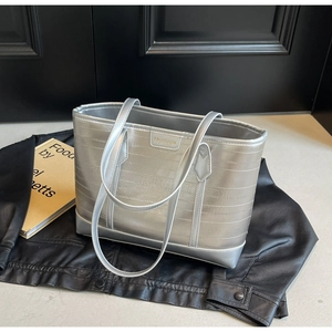 Detail of silver metallic tote bag featuring horizontal stitching and sleek handles