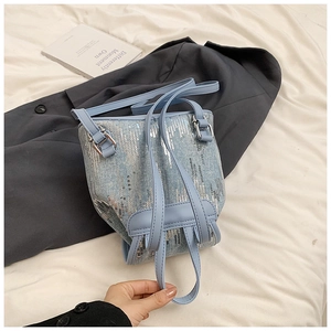 Gros plan du sac seau en denim bleu clair avec paillettes argentées et fermoirs en métal