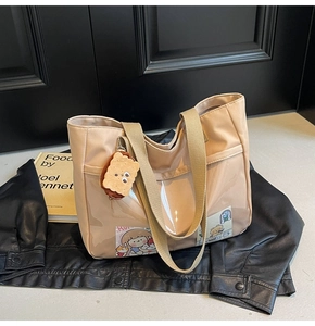 Detail of beige nylon tote bag with transparent PVC pocket and cute biscuit charm