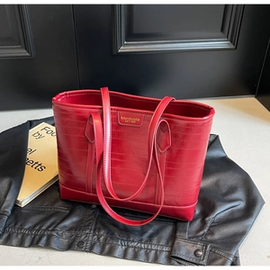 Detail of red embossed tote bag with brand plaque on a stylish black leather jacket