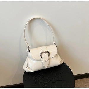 Détail d'un sac à bandoulière blanc crème avec un fermoir métallique en forme de cœur argenté