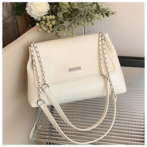 Close-up of cream white faux leather tote with chain strap and silver logo plaque