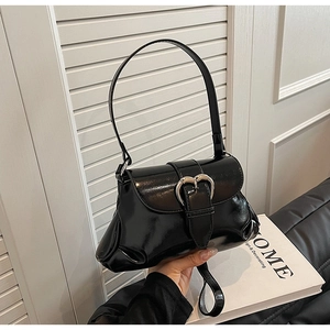 Close-up of black glossy saddle bag featuring a vintage silver heart-shaped metal buckle