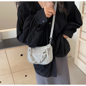 Detail of light gray leather handbag with silver chain and white pearl decoration