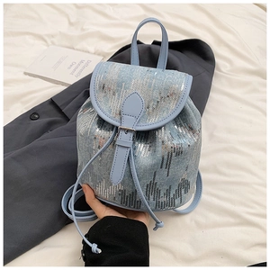 Gros plan du mini sac à dos en jean bleu clair à paillettes avec franges et cuir argenté