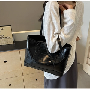 Close-up of black textured leather tote bag with glossy finish and dual strap design