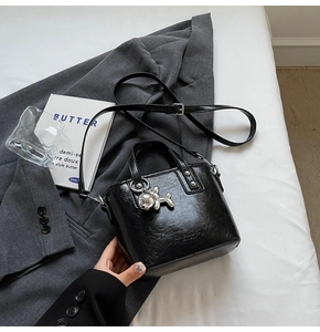 Detail of black leather bucket bag featuring a silver balloon dog charm and logo