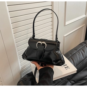 Detail of glossy black underarm bag featuring a silver heart-shaped metal buckle
