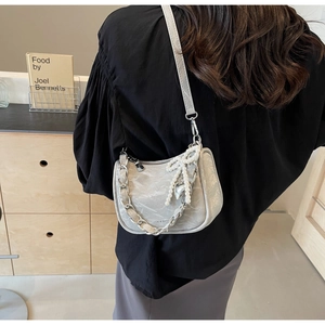 Detailed view of light gray textured crossbody bag with silver chain and heart charm