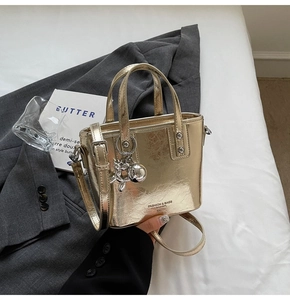 Close-up of metallic gold bucket bag featuring brand lettering and balloon dog charm detail