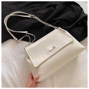 Close-up of white embossed tote bag with chic metal chain strap and logo plaque detail