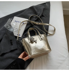 Detail of silver metallic bucket bag with balloon dog charm on a blazer background