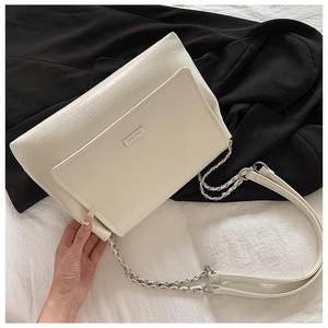 Detailed macro view of cream PU leather texture and metal logo plaque on the chain shoulder bag